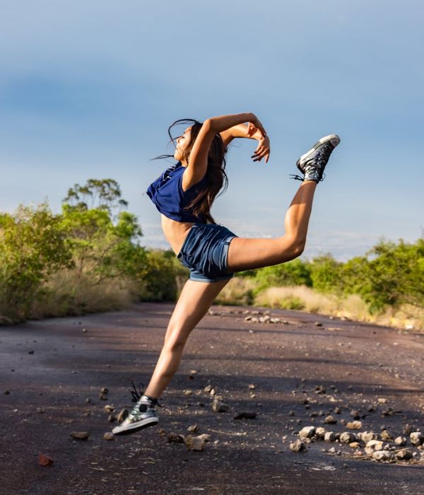 Woman performing a dynamic and energetic movement outdoors.
